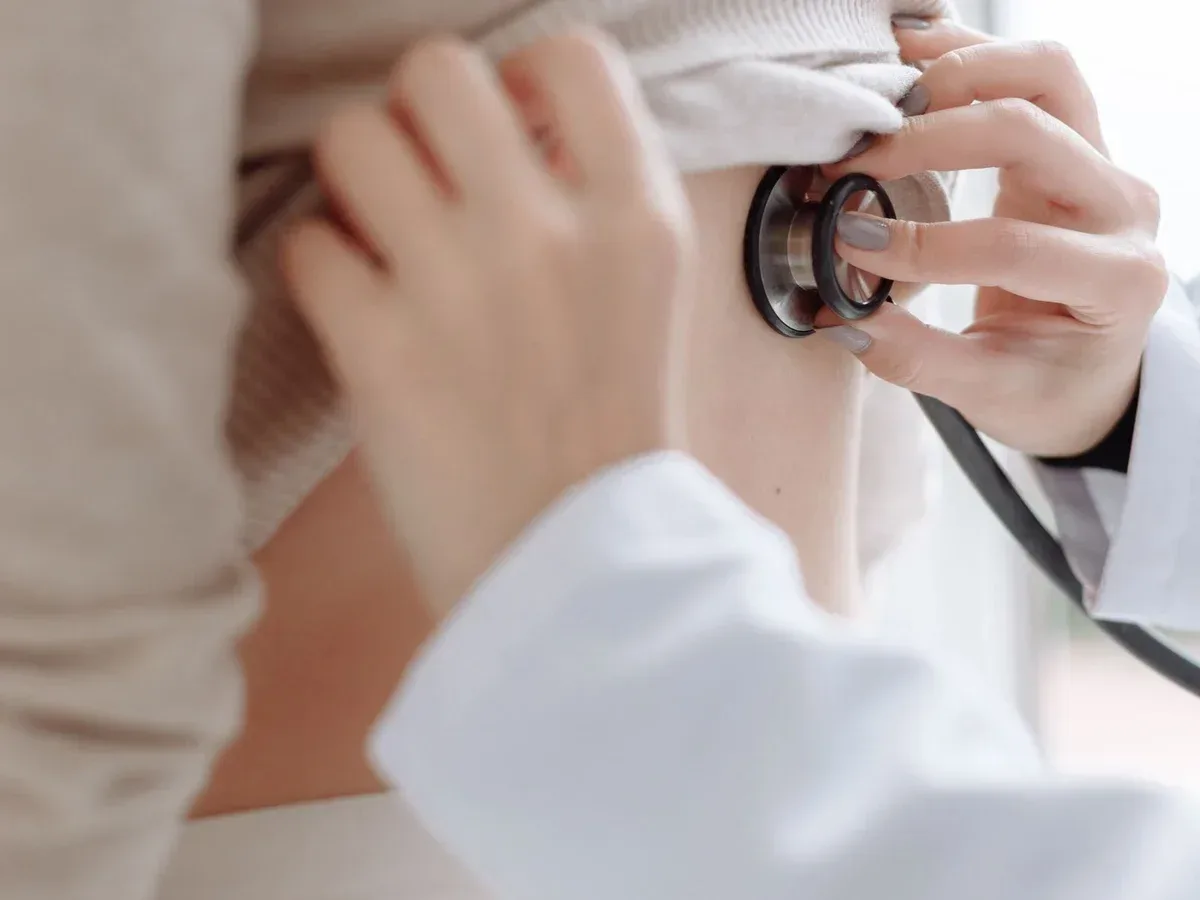 Detalhe de avaliação clínica com estetoscópio durante uma consulta, sem rostos visíveis — imagem ilustrativa.