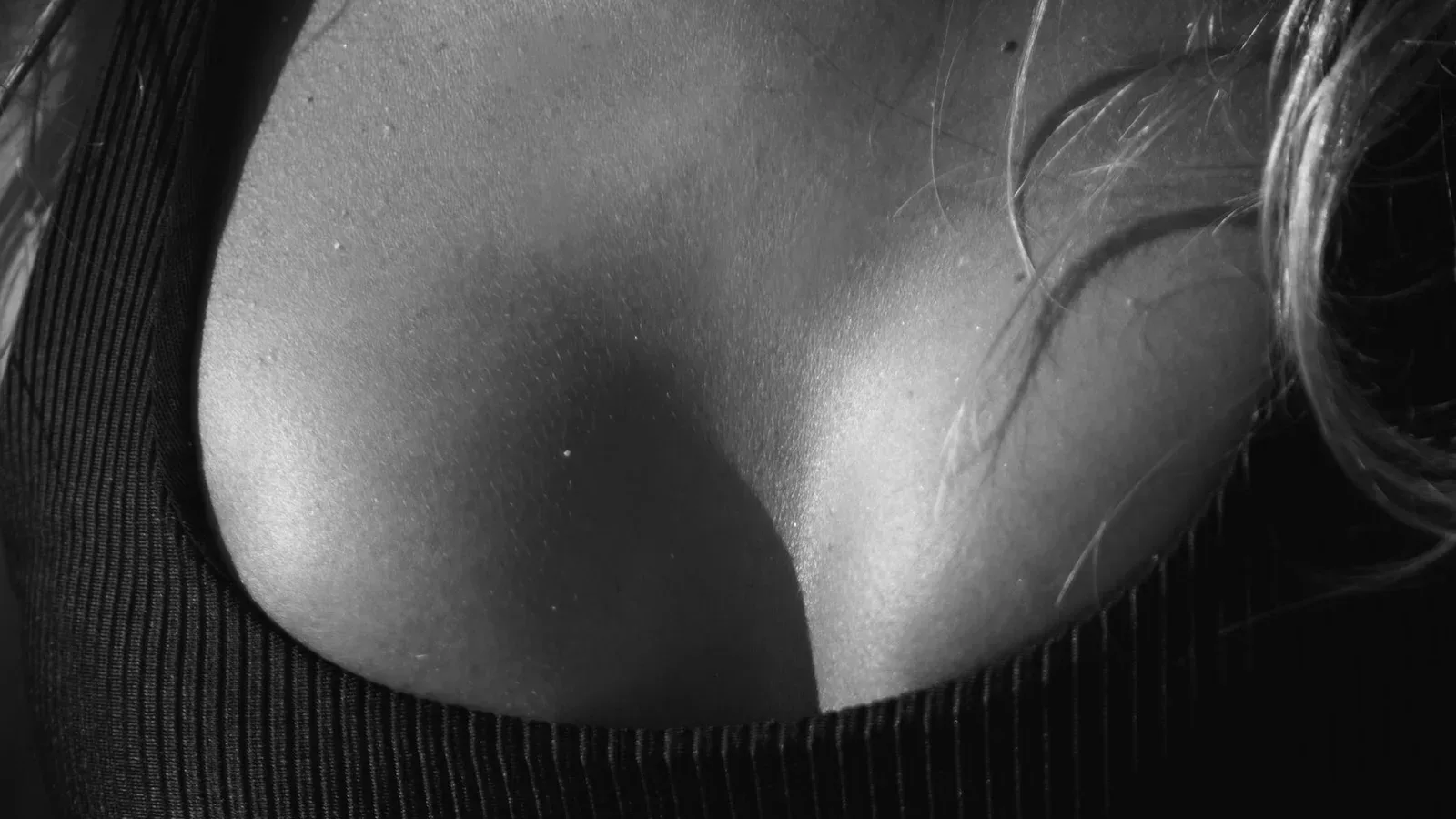 Detalhe de mulher com top esportivo preto, em fotografia monocromática — imagem ilustrativa.