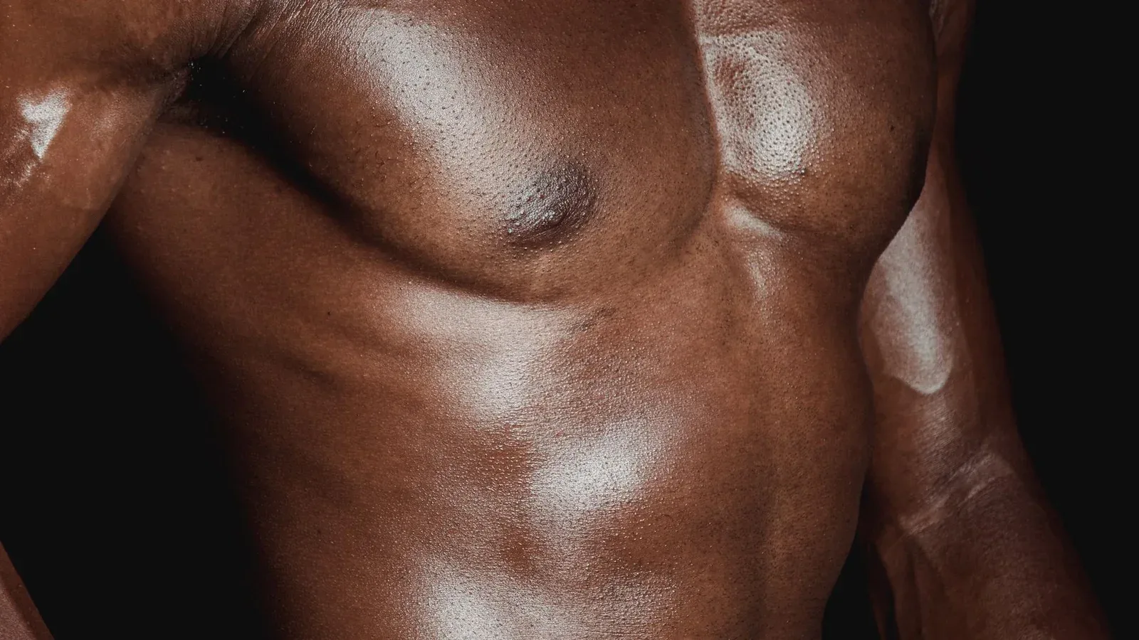 Detalhe de tórax e abdômen masculino em fundo escuro — imagem ilustrativa.